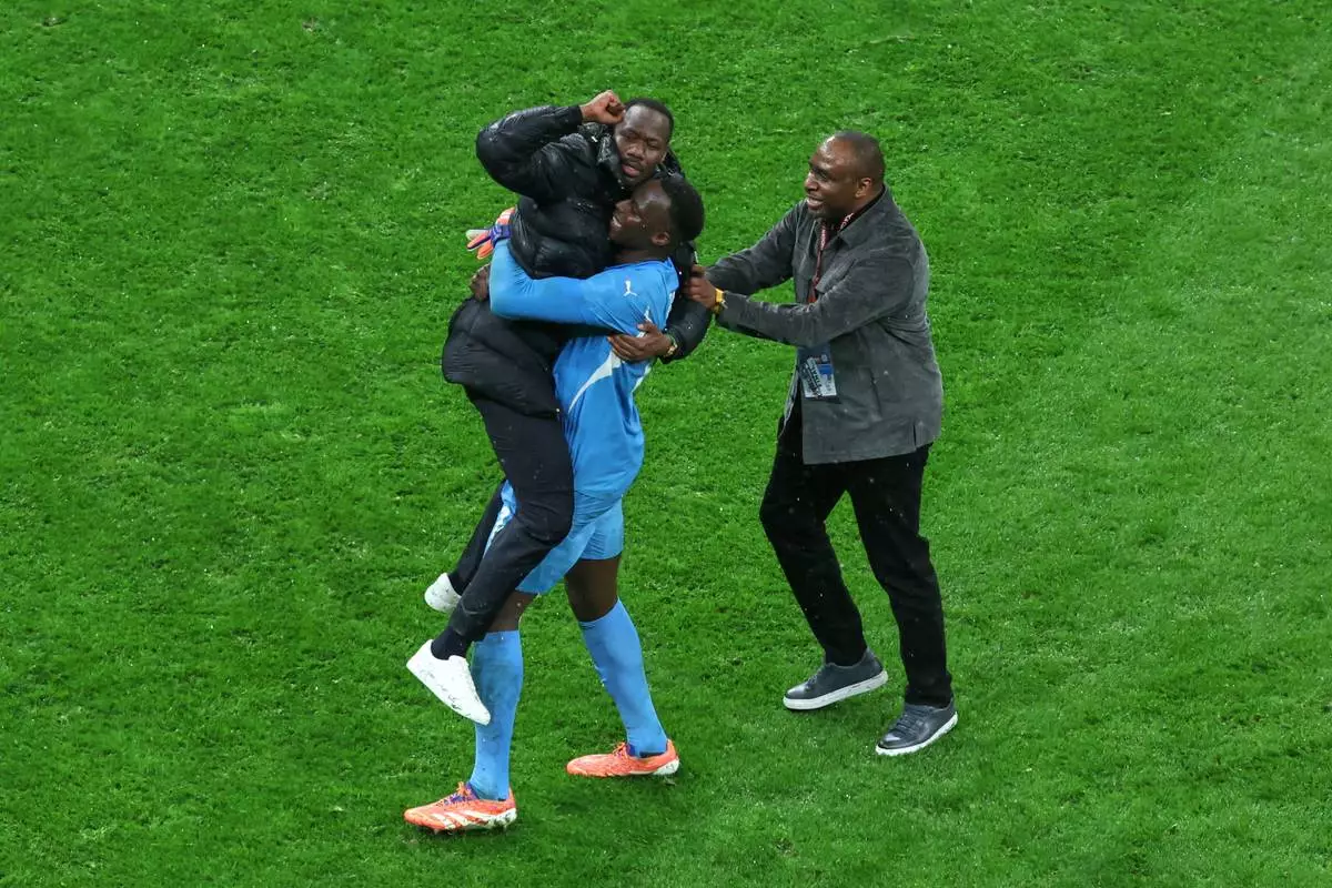 Senegal's head coach Pape Thiaw and Senegal's goalkeeper Edouard Osoque Mendy, center, celebrate after winning the Africa Cup of Nations final soccer match between Senegal and Morocco in Rabat, Morocco, Sunday, Jan. 18, 2026. (AP Photo/Youssef Loulidi)