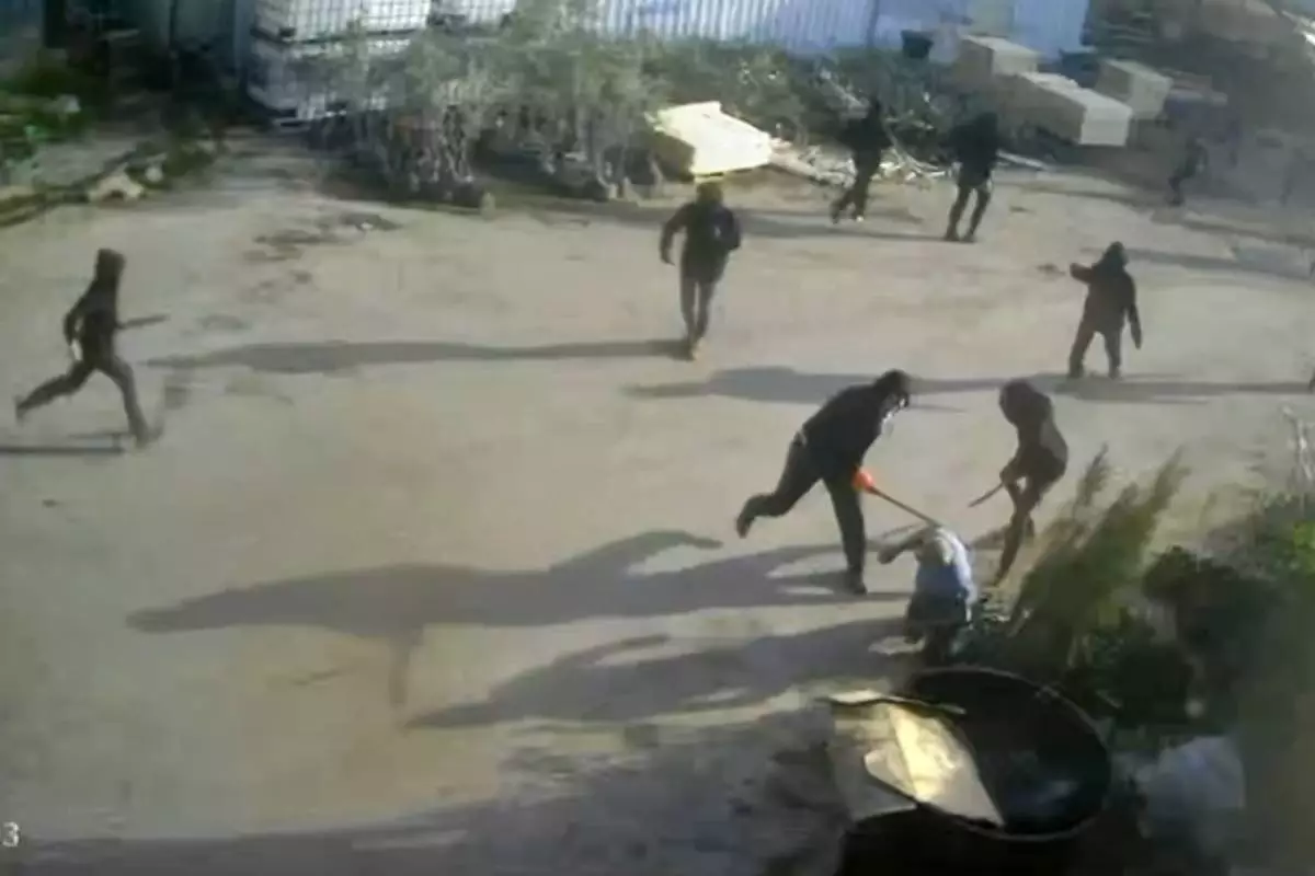 This frame grab from security camera footage filmed Jan. 8, 2026, and obtained by The Associated Press, shows men dressed mostly in black with their faces covered, two of whom are hitting a man on the ground as he tried to flee a nursery in the northern West Bank village of Deir Sharaf. Two people who witnessed the attack and are members of the family that owns the facility said the assailants were Israeli settlers beating 67-year-old Basim Saleh Yassin.(UGC via AP)