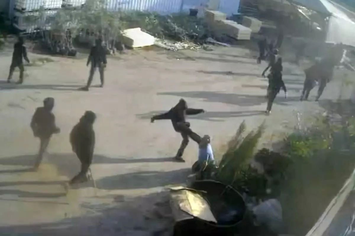 This frame grab from security camera footage filmed Jan. 8, 2026, and obtained by The Associated Press, shows men dressed mostly in black with their faces covered, one of whom is kicking a man on the ground as he tried to flee a nursery in the northern West Bank village of Deir Sharaf. Two people who witnessed the attack and are members of the family that owns the facility said the assailants were Israeli settlers beating 67-year-old Basim Saleh Yassin.(UGC via AP)