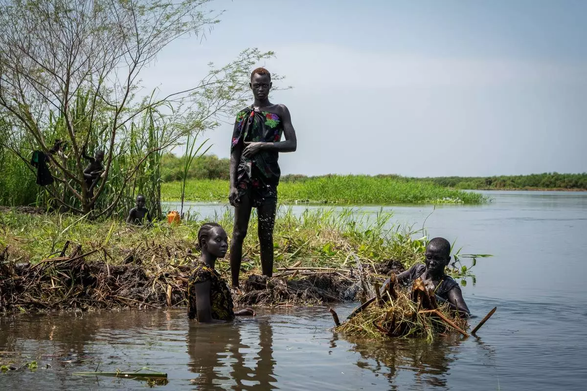 FILE - Ayen Deng Duot, far right, and her family reinforce their island with vegetation and mud from the swamp to prevent their home from being flooded along the Nile River in Akuak, South Sudan, Nov. 8, 2025. (AP Photo/Florence Miettaux, File)