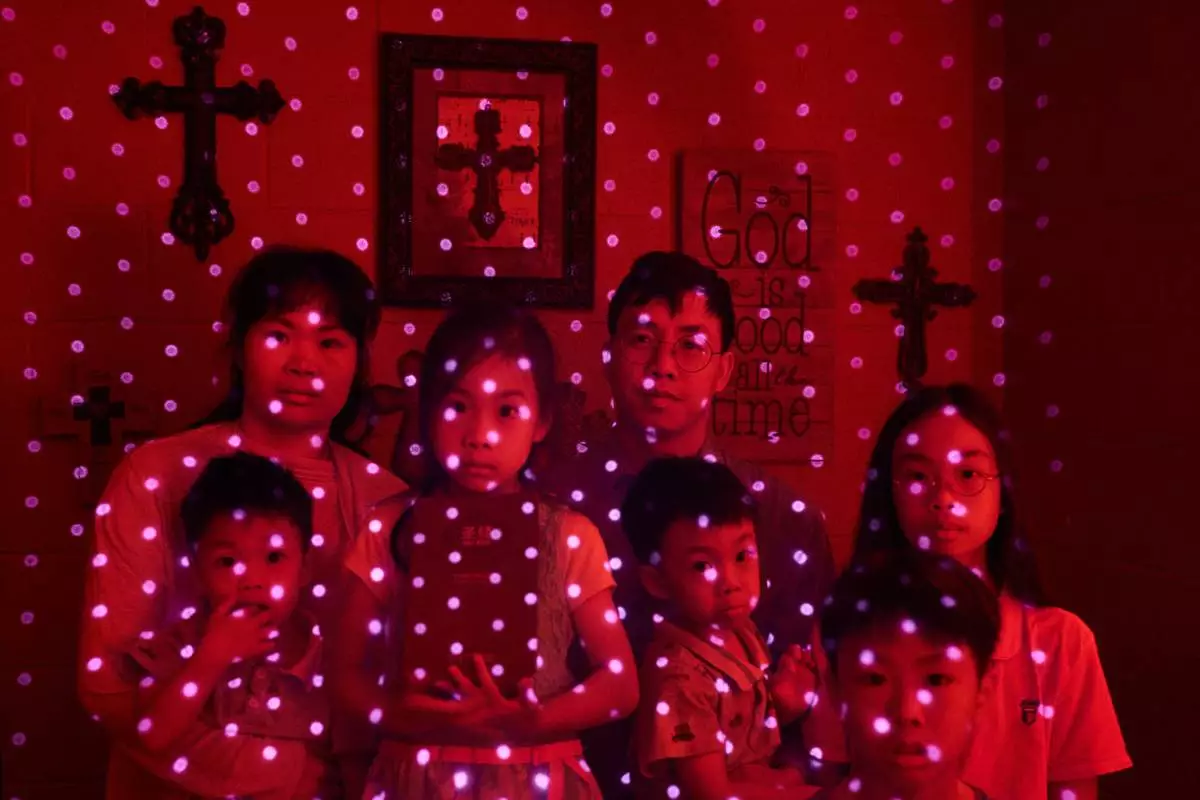 FILE - Members of a Chinese church living in exile after fleeing from China, are illuminated by beams of pulsed laser light from a cellphone's LiDAR scanner as they sit for a photo, Oct. 12, 2025, in Midland, Texas. Photographed are Wensheng Wen, rear right, his wife, Lou Guangyzing, and their children Xin, 11, from right, Gehua, 9, Jinghua, 3, Rou, 6, and Younghua, 3. (AP Photo/David Goldman, File)