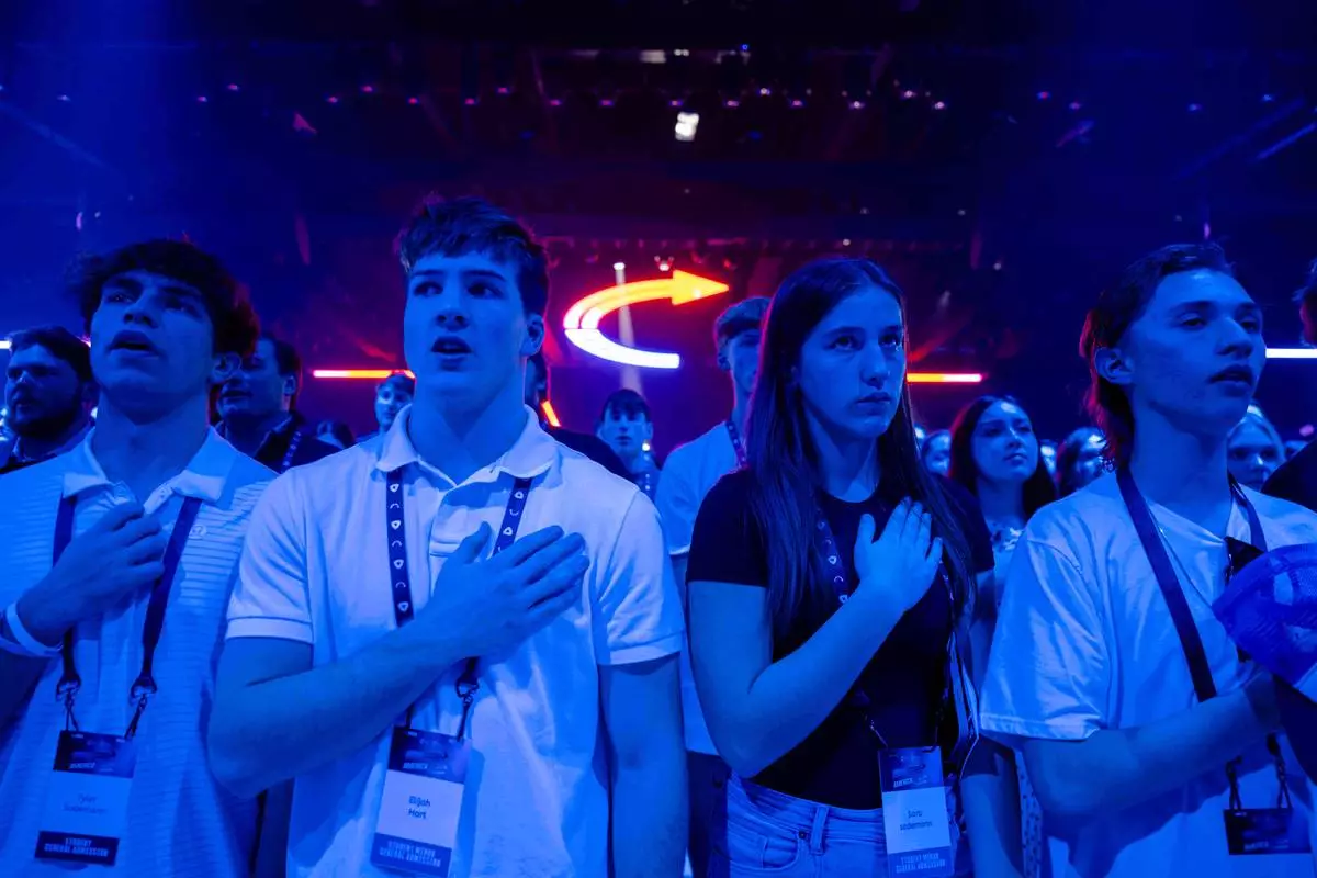 FILE - Attendees stand during Turning Point USA's AmericaFest 2025, Dec. 18, 2025, in Phoenix. (AP Photo/Jon Cherry, File)