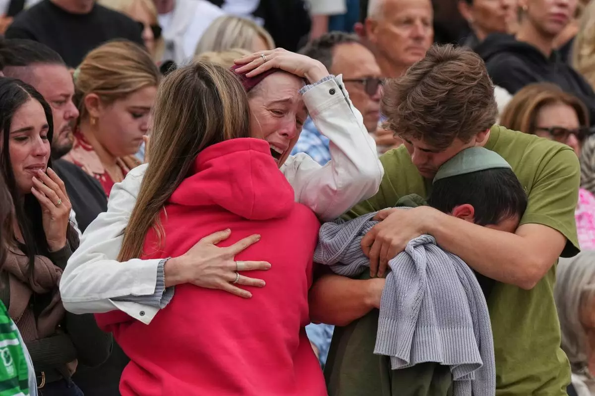 FILE - A family mourns during a menorah lighting ceremony for the victims of a shooting on Bondi Beach, in Sydney, Australia, Tuesday, Dec. 16, 2025. (AP Photo/Mark Baker, File)