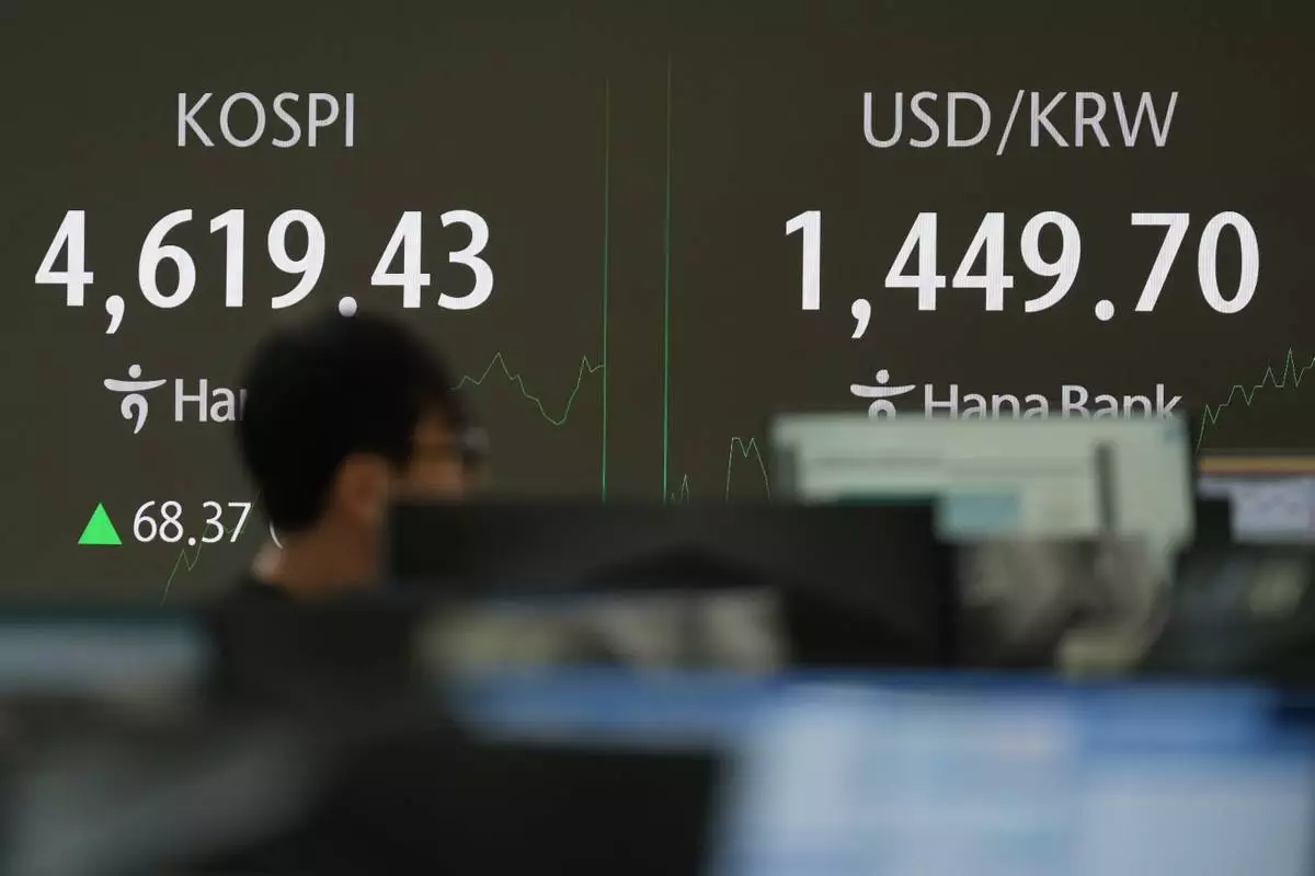A dealer walks past near the screens showing the Korea Composite Stock Price Index (KOSPI), left, and the foreign exchange rate between U.S. dollar and South Korean won at a dealing room of Hana Bank in Seoul, South Korea, Thursday, Jan. 8, 2026. (AP Photo/Lee Jin-man)
