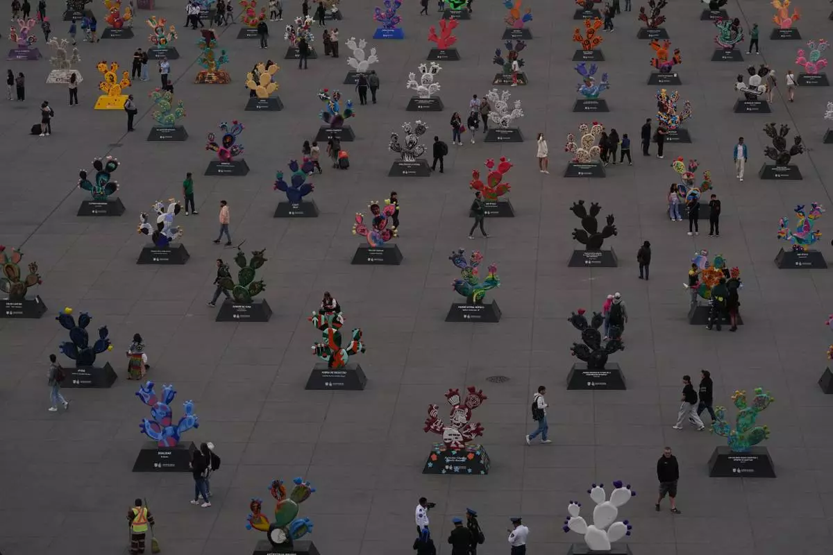 People walk among structures of nopales, prickly pear cacti, at the National Palace in Mexico City's main square, the Zócalo, Tuesday, Jan. 27, 2026. (AP Photo/Marco Ugarte)