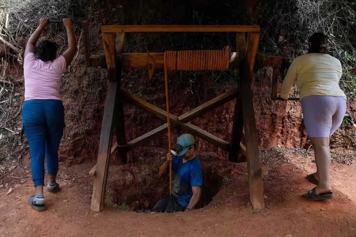 Women lower a miner into a gold mine pit in El Callao, Venezuela, Tuesday, Jan. 22, 2026. (AP Photo/Matias Delacroix)