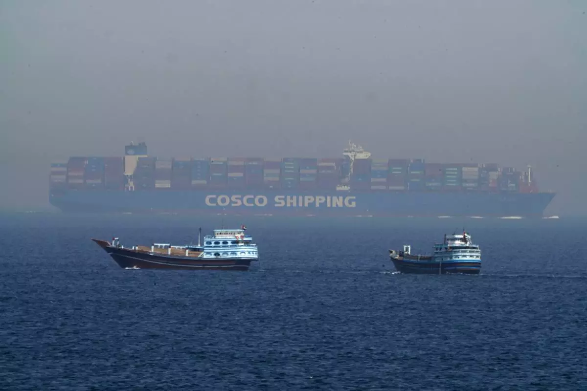 FILE - Two traditional dhows sail by a large container ship in the Strait of Hormuz, May 19, 2023. (AP Photo/Jon Gambrell, File)