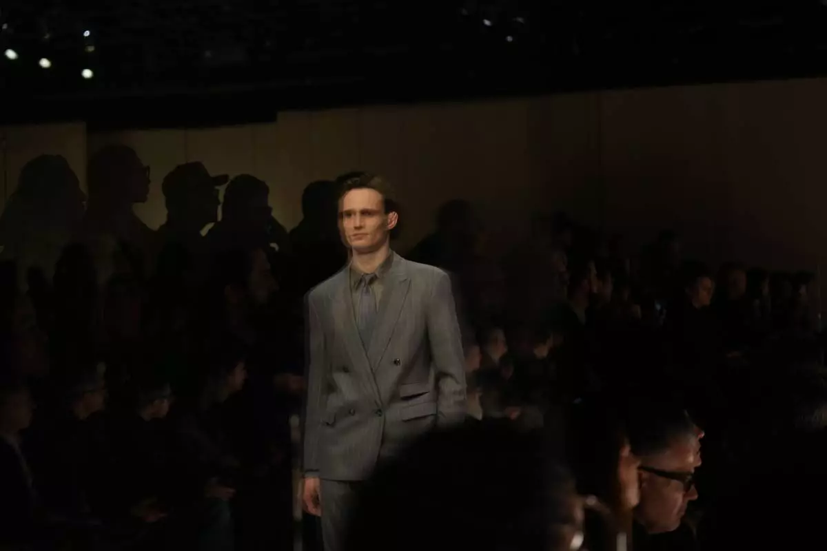 A model is reflected on a glass while wearing a creation as part of the Giorgio Armani Fall/Winter 2026-2027 Men's collection presented in Milan, Italy, Monday, Jan. 19, 2026. (AP Photo/Antonio Calanni)