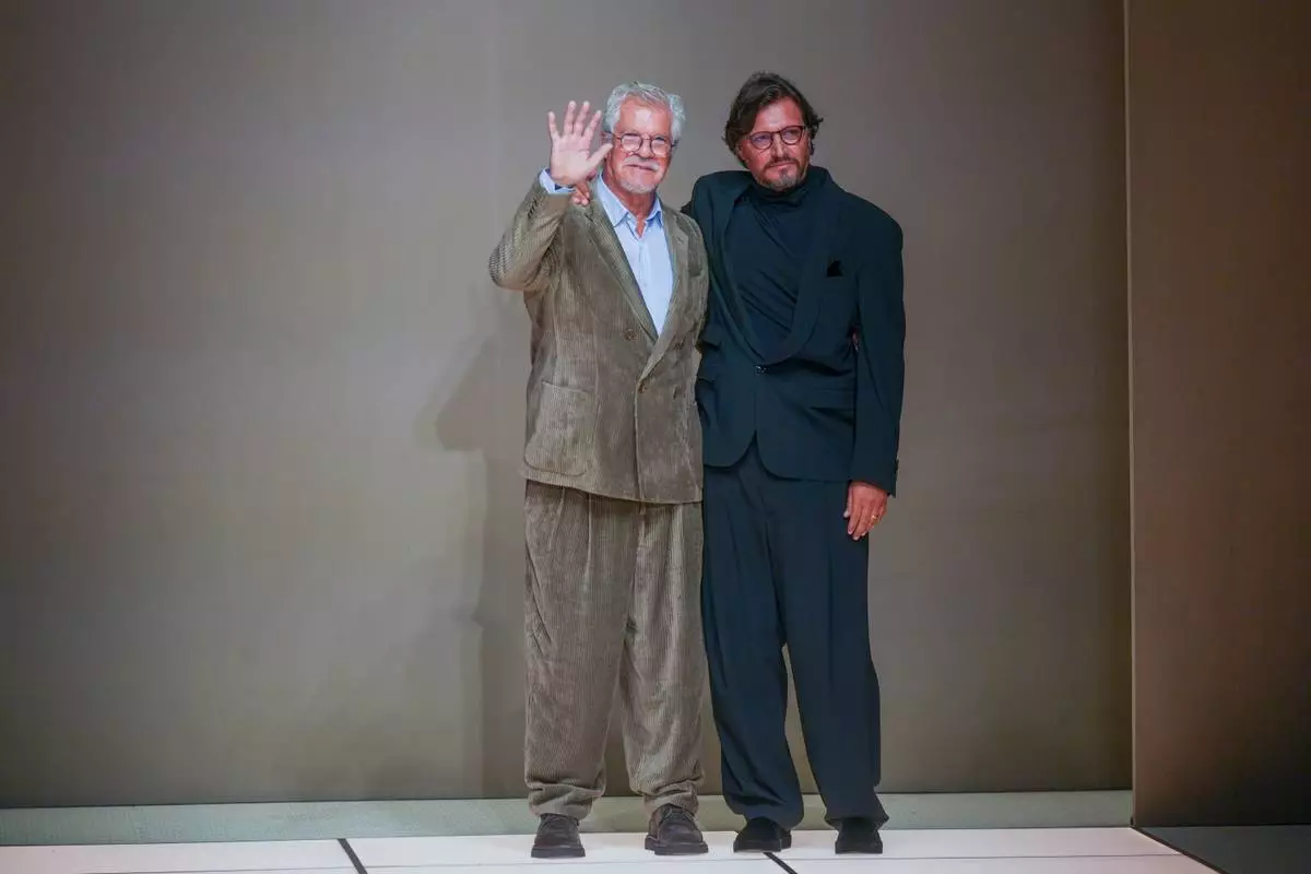 Fashion designers Leo Dell'Orco, left, and Gianluca Dell'Orco acknowledge applauses at the end of the Giorgio Armani Fall/Winter 2026-2027 Men's collection presented in Milan, Italy, Monday, Jan. 19, 2026. (AP Photo/Antonio Calanni)