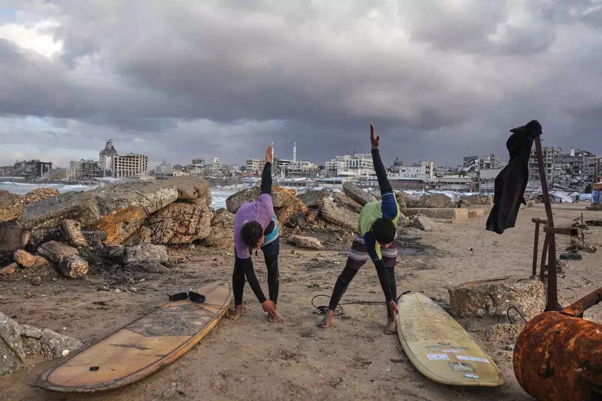 FILE - Palestinian Khalil Abu Jayyab, right, and Tahseen Abu Assi warm up before surfing on the beach in Gaza City, Dec. 28, 2025. (AP Photo/Jehad Alshrafi, File)