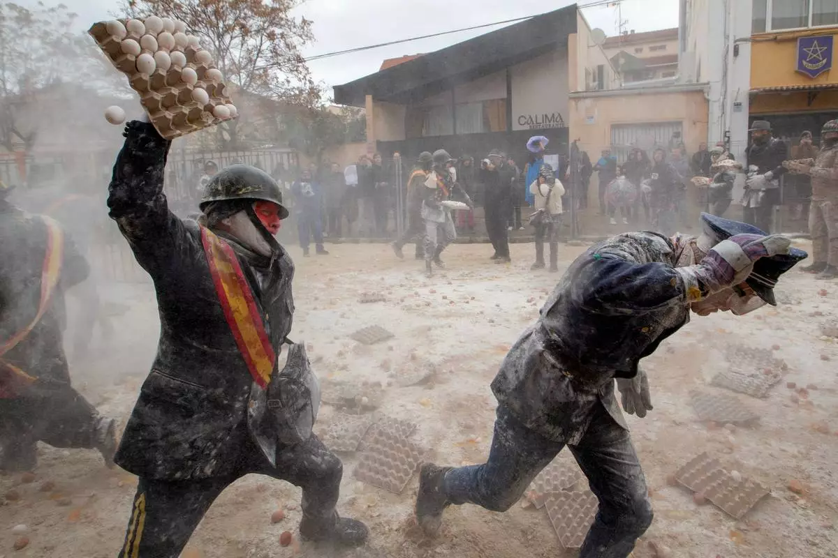 FILE - Revelers take part in the Els Enfarinats festival, a battle using flour, eggs and firecrackers, in the town of Ibi near Alicante, Spain, Dec. 28, 2025. (AP Photo/Alberto Saiz File)