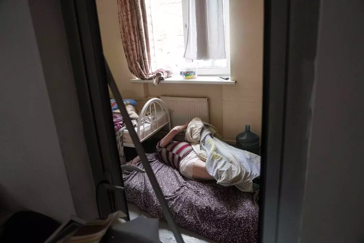 FILE - En elderly man lies on the floor at a hospice after it was damaged after a Russian strike on Kyiv, Ukraine, Dec. 27, 2025. (AP Photo/Evgeniy Maloletka, File)