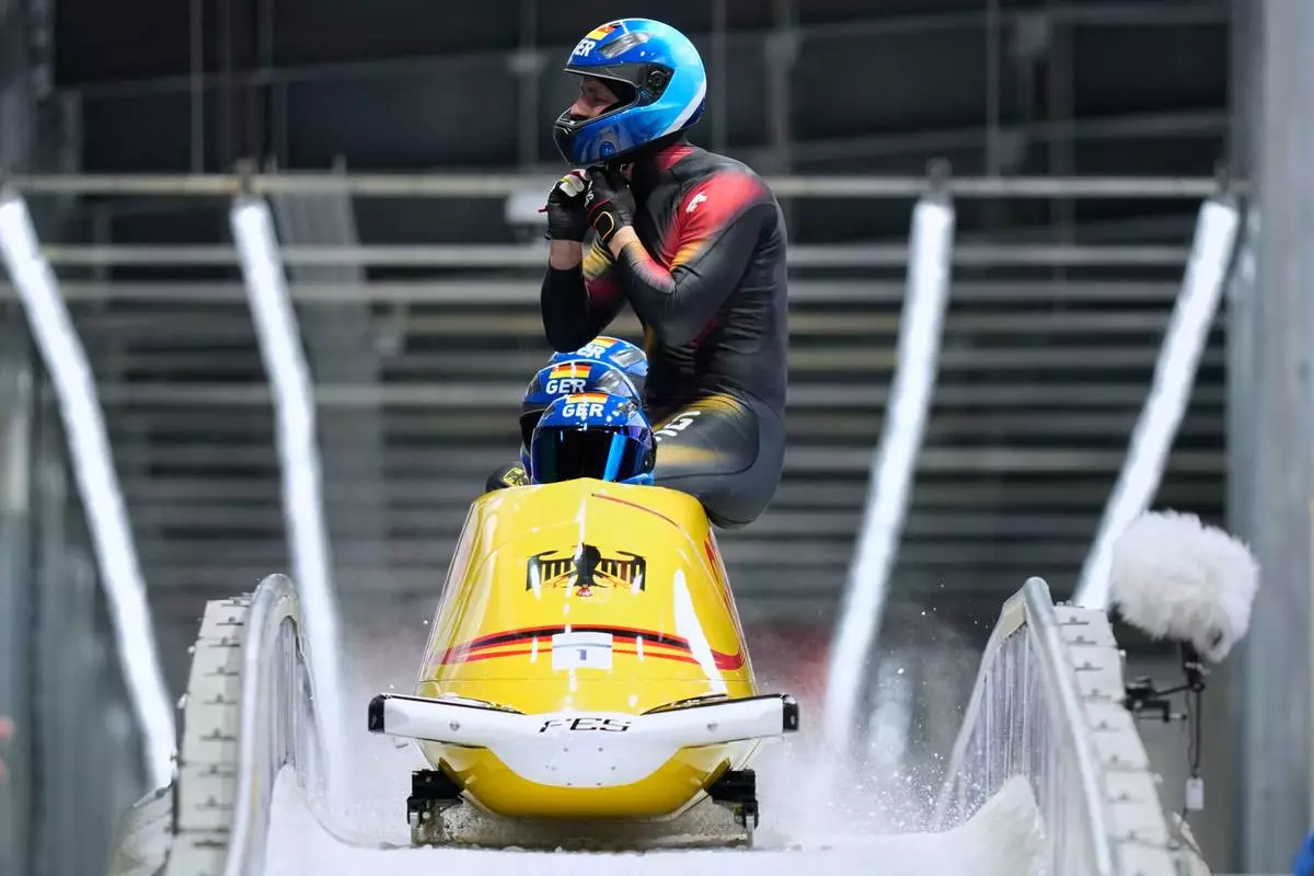 Germany's Johannes Lochner, front, Thorsten Margis, Jorn Wenzel and Georg Fleischauer arrive at the finish during a four man bobsled run at the 2026 Winter Olympics, in Cortina d'Ampezzo, Italy, Sunday, Feb. 22, 2026. (AP Photo/Aijaz Rahi)