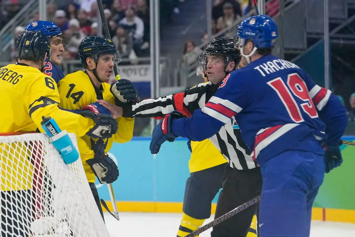 Sweden's Joel Eriksson Ek (14) and United States' Matthew Tkachuk (19) are kept apart during the second period of a men's ice hockey quarterfinal game at the 2026 Winter Olympics, in Milan, Italy, Wednesday, Feb. 18, 2026. (AP Photo/Hassan Ammar)