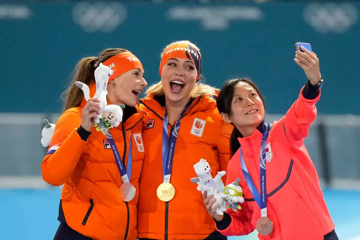 Jutta Leerdam of the Netherlands, center and gold medal, Femke Kok of the Netherlands, left and silver medal, and Japan's Miho Takagi, right and bronze medal, celebrate on the podium after the women's 1,000 meters speedskating race at the 2026 Winter Olympics, in Milan, Italy, Monday, Feb. 9, 2026. (AP Photo/Luca Bruno)