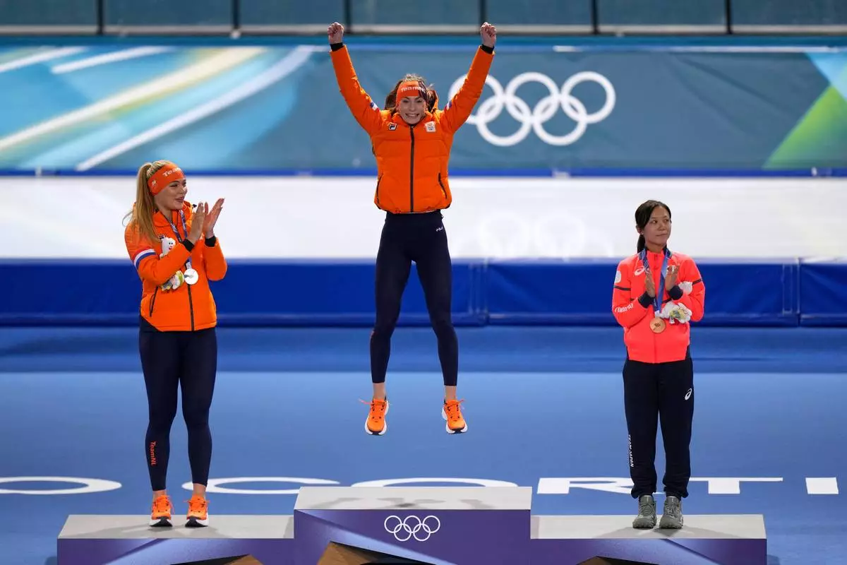 Femke Kok of the Netherlands, center and gold medal celebrates with Jutta Leerdam of the Netherlands, left and silver medal, and Miho Takagi of Japan, right and bronze medal, on the podium of the women's 500 meters speedskating race at the 2026 Winter Olympics, in Milan, Italy, Sunday, Feb. 15, 2026. (AP Photo/Luca Bruno)