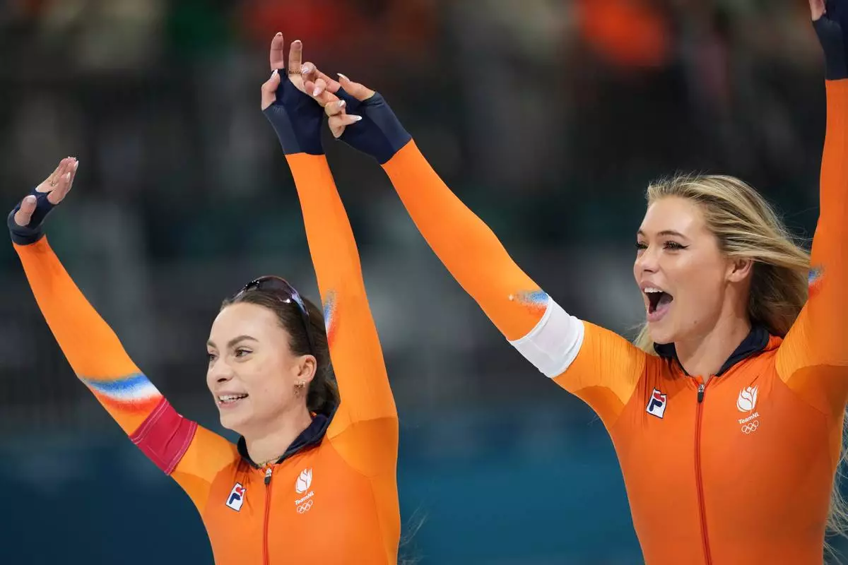 Femke Kok of the Netherlands, left, celebrates winning a gold medal with silver medallist Jutta Leerdam of the Netherlands, right, in the women's 500 meters speedskating race at the 2026 Winter Olympics, in Milan, Italy, Sunday, Feb. 15, 2026. (AP Photo/Antonio Calanni)
