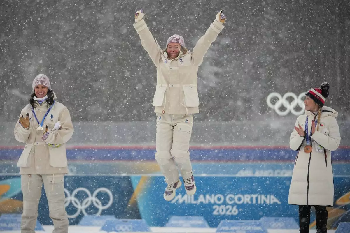 Gold medalist Oceane Michelon, of France, center, jumps on the podium during a victory ceremony next to silver medalist Julia Simon, of France, left, and bronze medalist Tereza Vobornikova, of Czechia, after the women's 12.5-kilometer mass start biathlon race at the 2026 Winter Olympics in Anterselva, Italy, Saturday, Feb. 21, 2026. (AP Photo/Andrew Medichini)