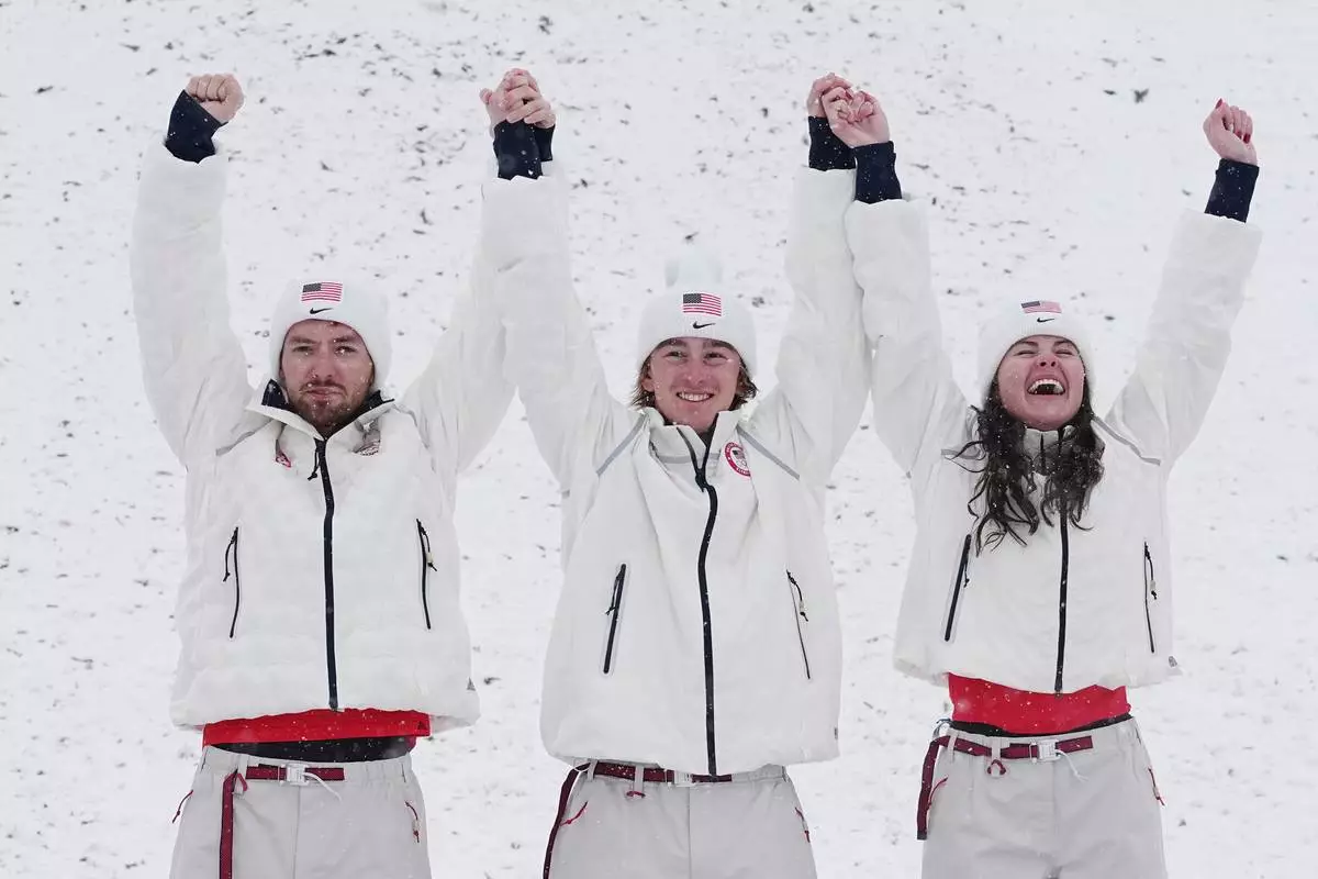 From left, gold medalists United States' Christopher Lillis, Connor Curran and Kaila Kuhn celebrates after the freestyle skiing mixed team aerials final at the 2026 Winter Olympics, in Livigno, Italy, Saturday, Feb. 21, 2026. (AP Photo/Gregory Bull)