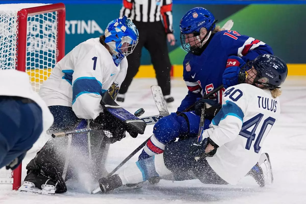 Finland's Sanni Ahola and Finland's Noora Tulus, right, make a save against United States' Grace Zumwinkle during a preliminary round match of women's ice hockey between the United States and Finland at the 2026 Winter Olympics, in Milan, Italy, Saturday, Feb. 7, 2026. (AP Photo/Petr David Josek)