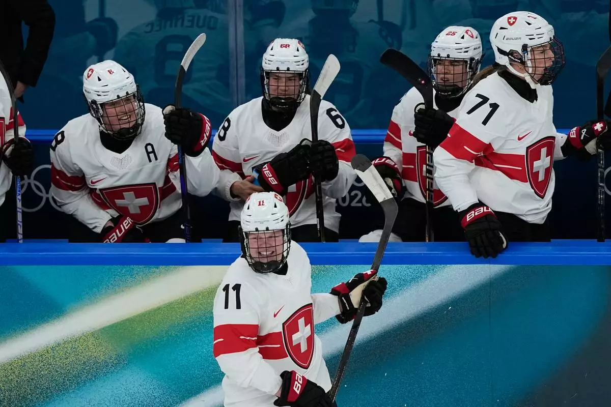 Switzerland's Laura Zimmermann, center, celebrates after scoring her side's opening goal during a preliminary round match of women's ice hockey between Switzerland and Czechia at the 2026 Winter Olympics, in Milan, Italy, Friday, Feb. 6, 2026. (AP Photo/Hassan Ammar)