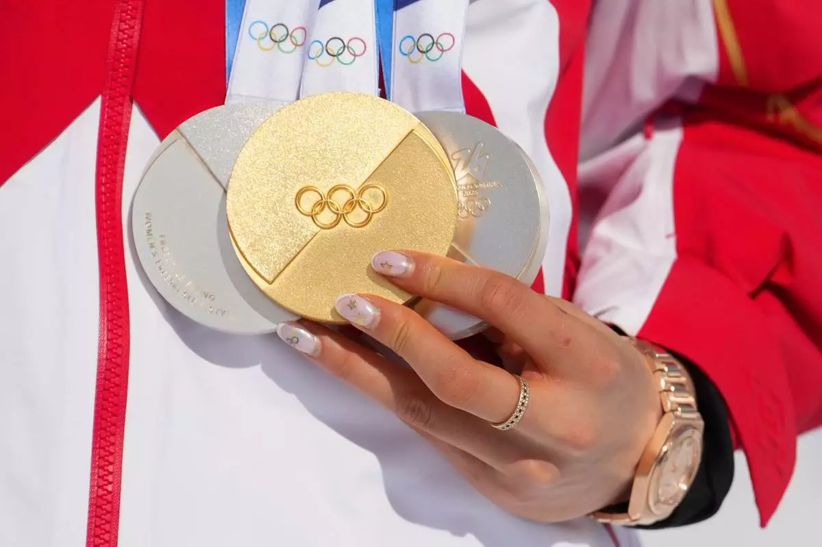 China's Eileen Gu holds her gold medal alongside her two silver medals after the women's freestyle skiing halfpipe final at the 2026 Winter Olympics, in Livigno, Italy, Sunday, Feb. 22, 2026. (AP Photo/Lindsey Wasson)