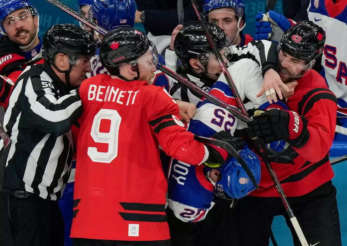 Referees try to break up a fight between Canada's Sam Bennett (9), United States' Charlie McAvoy (25) and Canada's Tom Wilson (43) during the second period of the men's ice hockey gold medal game at the 2026 Winter Olympics, in Milan, Italy, Sunday, Feb. 22, 2026. (AP Photo/Luca Bruno)