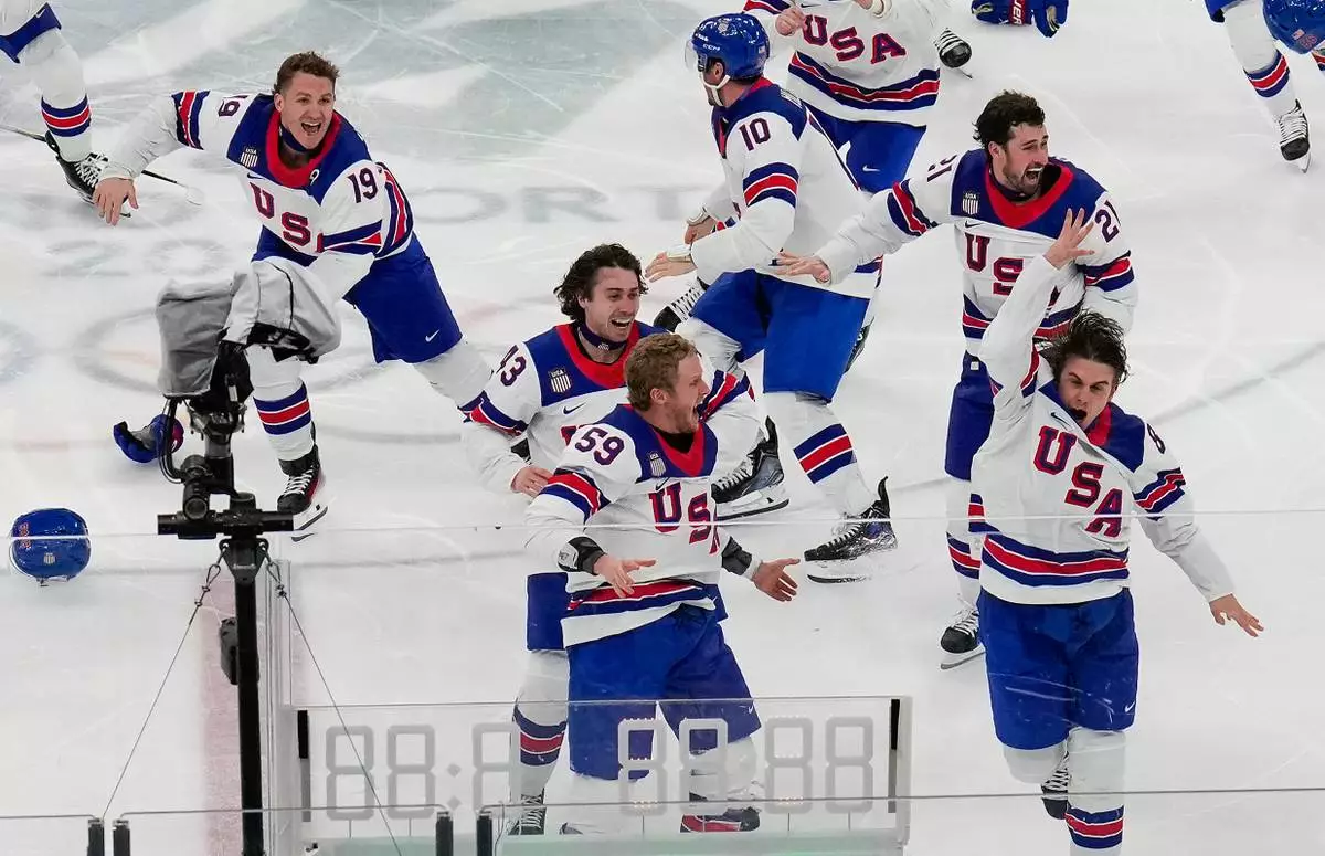 United States' Jack Hughes (86), right, celebrates with teammates after scoring the game winning goal against Canada in sudden death overtime during the men's ice hockey gold medal game at the 2026 Winter Olympics, in Milan, Italy, Sunday, Feb. 22, 2026. (AP Photo/Luca Bruno)