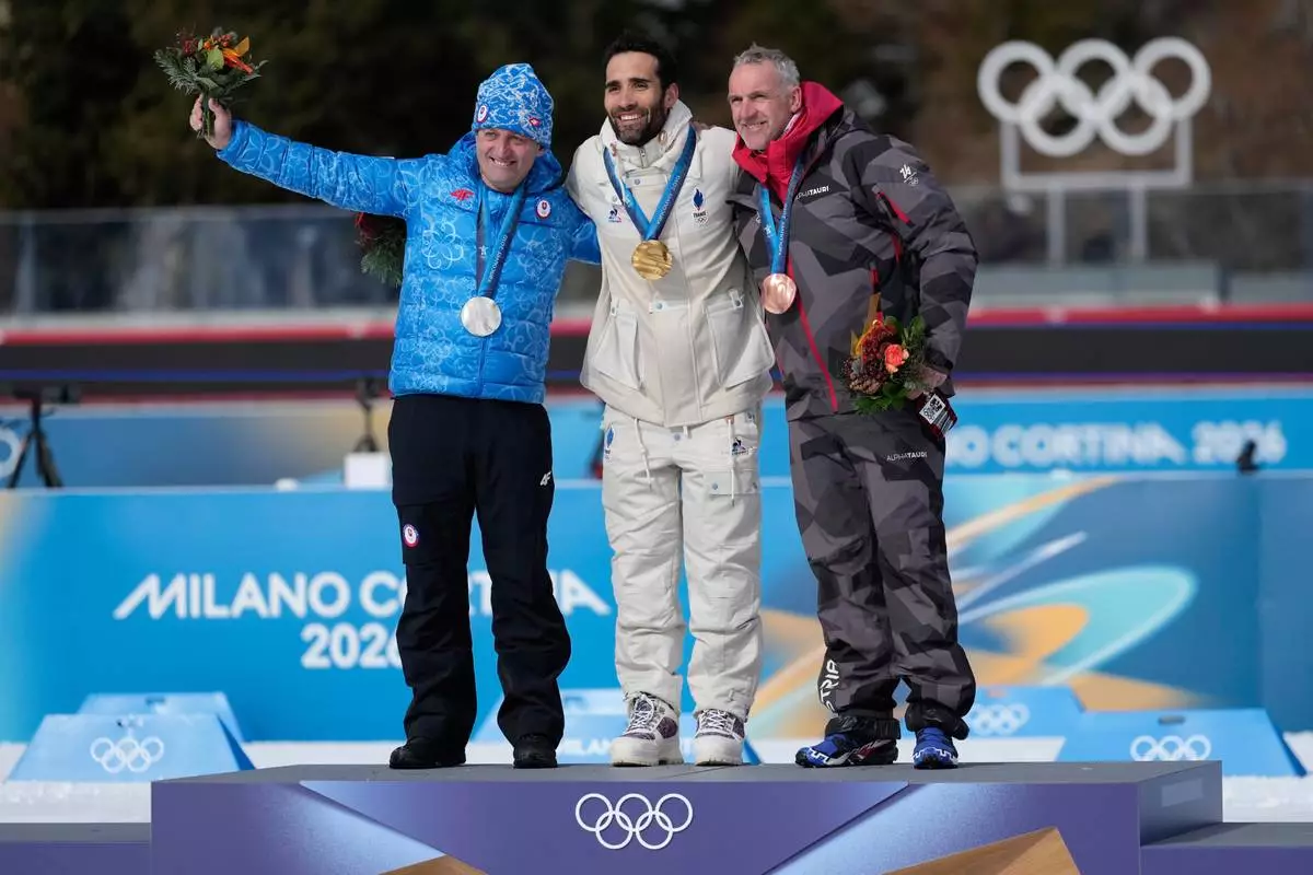 Martin Fourcade, of France, center, poses with the gold medal for the men's 15-kilometer mass start biathlon race from the 2010 Vancouver Winter Olympics with silver medalist Pavol Hurajt, of Slovakia, left, and bronze medalist Christoph Sumann, of Austria, during a reallocation medals ceremony at the 2026 Winter Olympics in Anterselva, Italy, Sunday, Feb. 15, 2026. (AP Photo/Mosa'ab Elshamy)