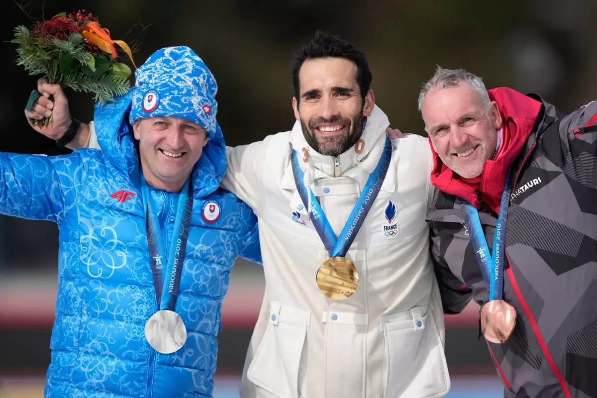 Martin Fourcade, of France, center, poses with the gold medal for the men's 15-kilometer mass start biathlon race from the 2010 Vancouver Winter Olympics with silver medalist Pavol Hurajt, of Slovakia, left, and bronze medalist Christoph Sumann, of Austria, during a reallocation medals ceremony at the 2026 Winter Olympics in Anterselva, Italy, Sunday, Feb. 15, 2026. (AP Photo/Mosa'ab Elshamy)