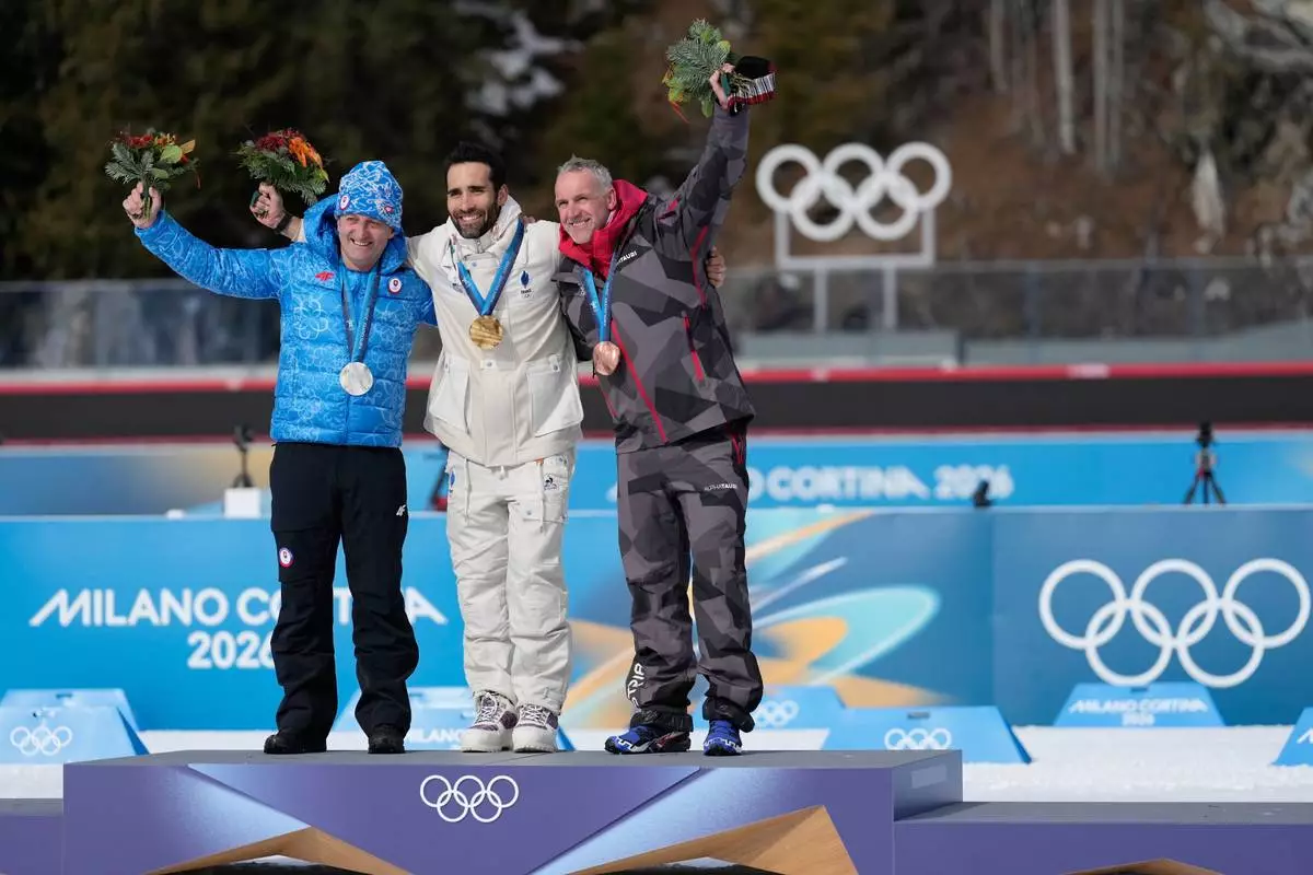 Martin Fourcade, of France, center, poses with the gold medal for the men's 15-kilometer mass start biathlon race from the 2010 Vancouver Winter Olympics with Pavol Hurajt, of Slovakia, left, and Christoph Sumann, of Austria, during a reallocation medals ceremony at the 2026 Winter Olympics in Anterselva, Italy, Sunday, Feb. 15, 2026. (AP Photo/Mosa'ab Elshamy)