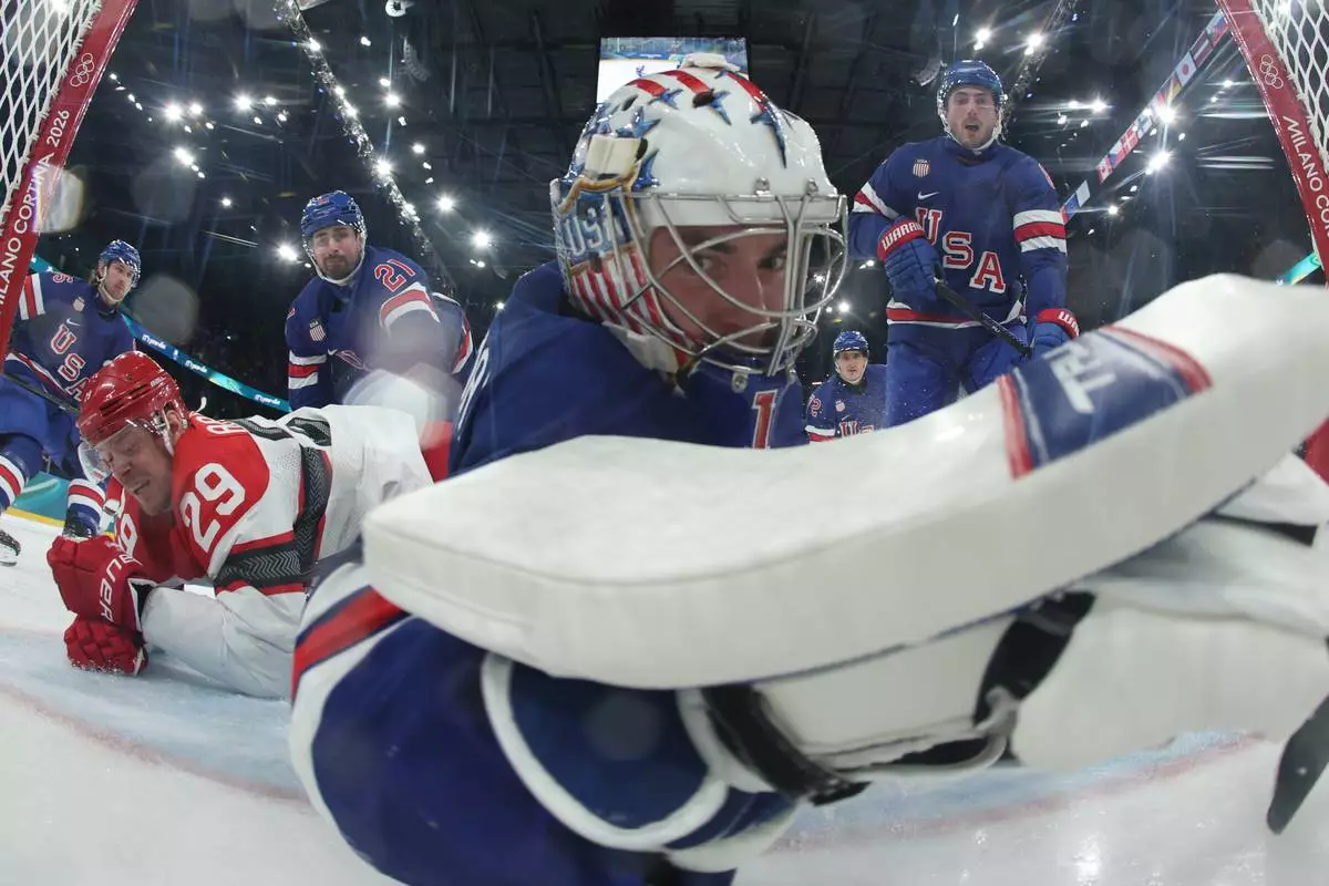 United States' goalkeeper Jeremy Swayman dives to makes a save as Denmark's Nick Olesen scores his side's opening goal during a preliminary round game of men's ice hockey between the United States and Denmark at the 2026 Winter Olympics, in Milan, Italy, Saturday, Feb. 14, 2026. (Bruce Bennett/Pool Photo via AP)