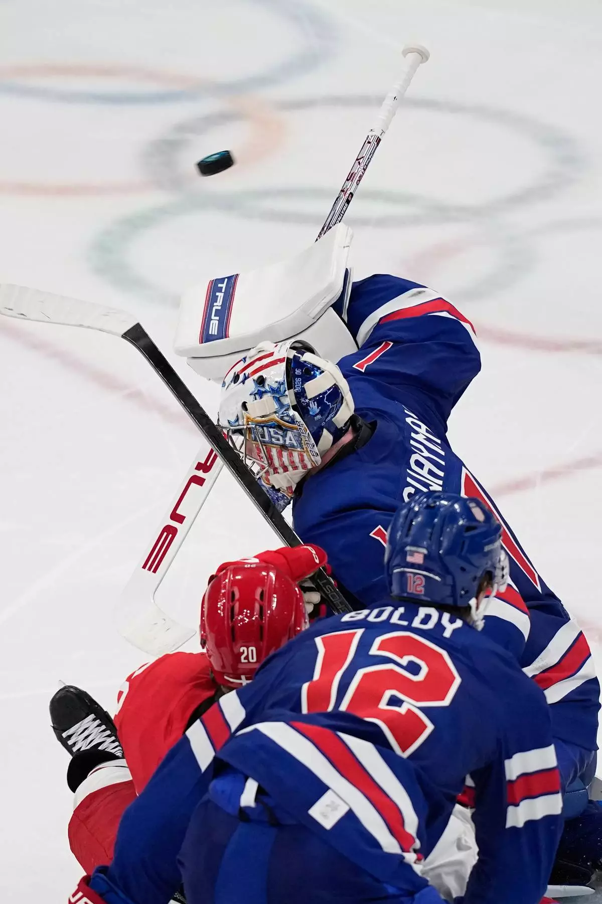 United States' goalkeeper Jeremy Swayman, right, makes a save against Denmark's Lars Eller, center, during a preliminary round match of men's ice hockey between United States and Denmark at the 2026 Winter Olympics, in Milan, Italy, Saturday, Feb. 14, 2026. (AP Photo/Petr David Josek)