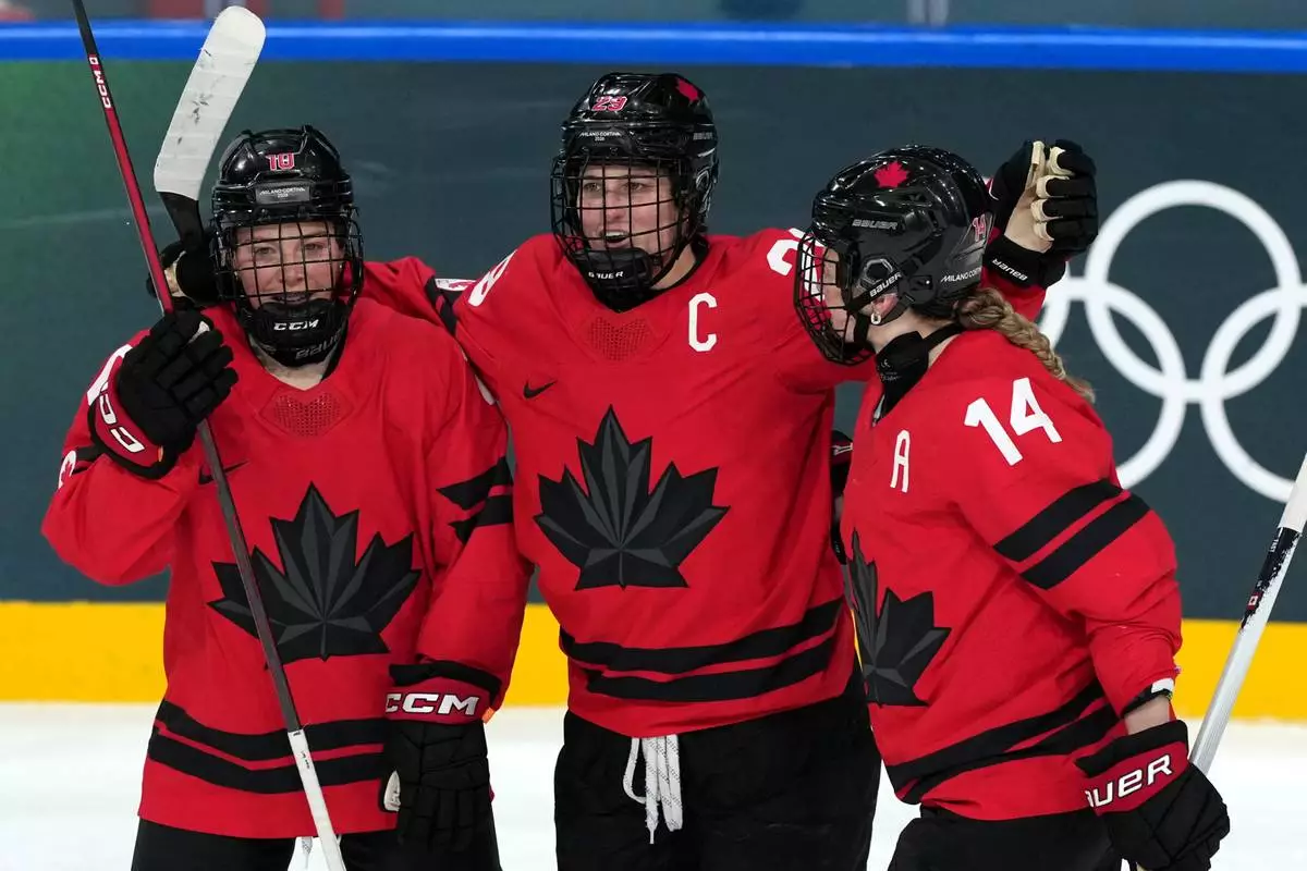 Canada's Marie-Philip Poulin (29) celebrates with Sarah Fillier (10) and Renata Fast (14) after Poulin scored against Germany during the third period of a women's ice hockey quarterfinal match at the 2026 Winter Olympics, in Milan, Italy, Saturday, Feb. 14, 2026. (AP Photo/Carolyn Kaster)