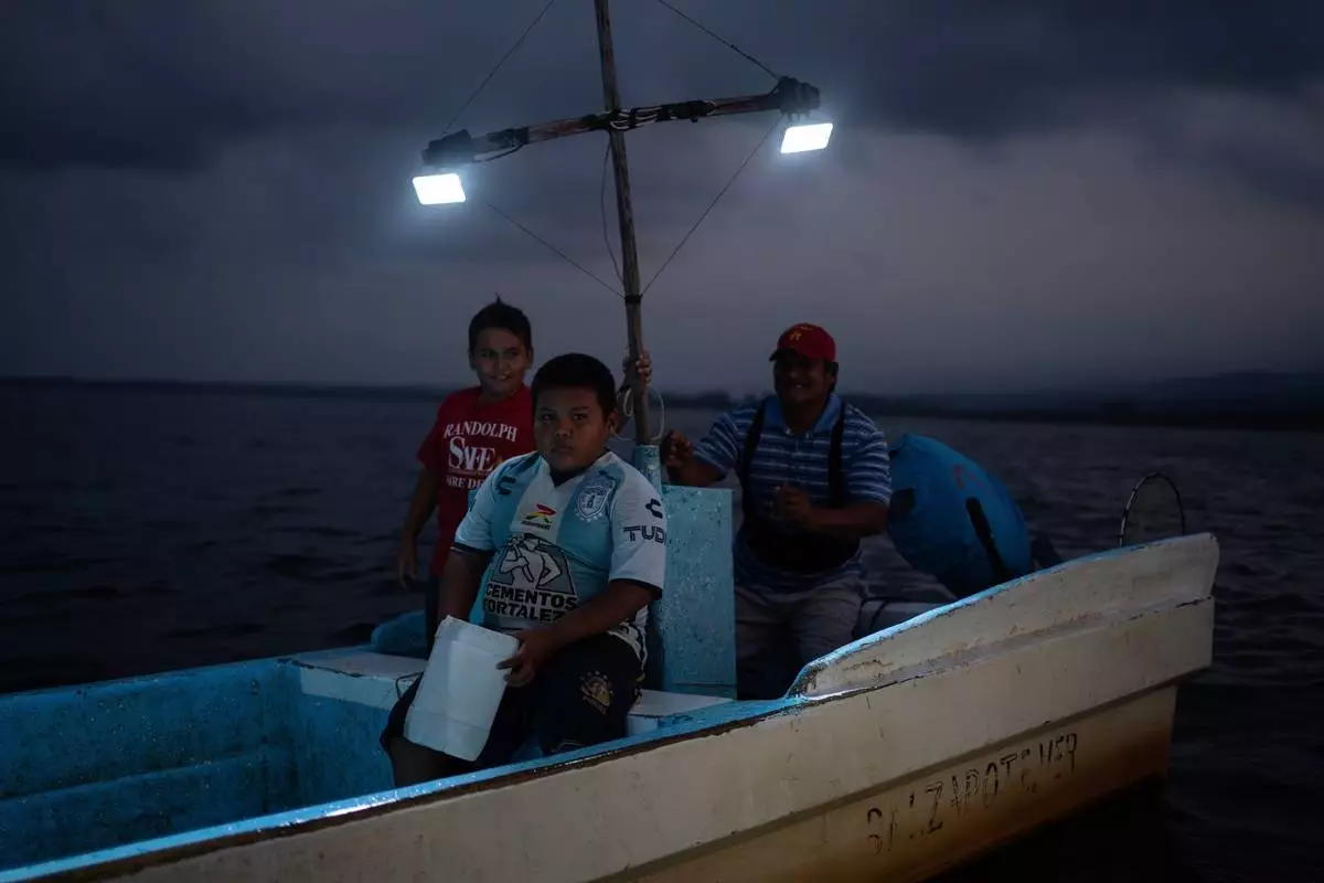 FILE - Fisherman Pancho Contreras sails at sea with young fishermen as night falls near Los Arrecifes, Mexico, Oct. 26, 2025. (AP Photo/Felix Marquez, File)