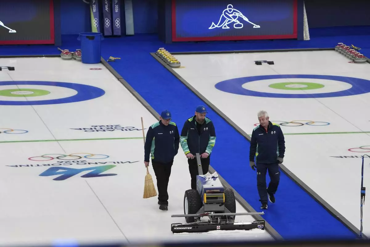 Staff members level the ice before the bronze medal curling mixed doubles match at the 2026 Winter Olympics, in Cortina d'Ampezzo, Italy, Tuesday, Feb. 10, 2026. (AP Photo/Misper Apawu)