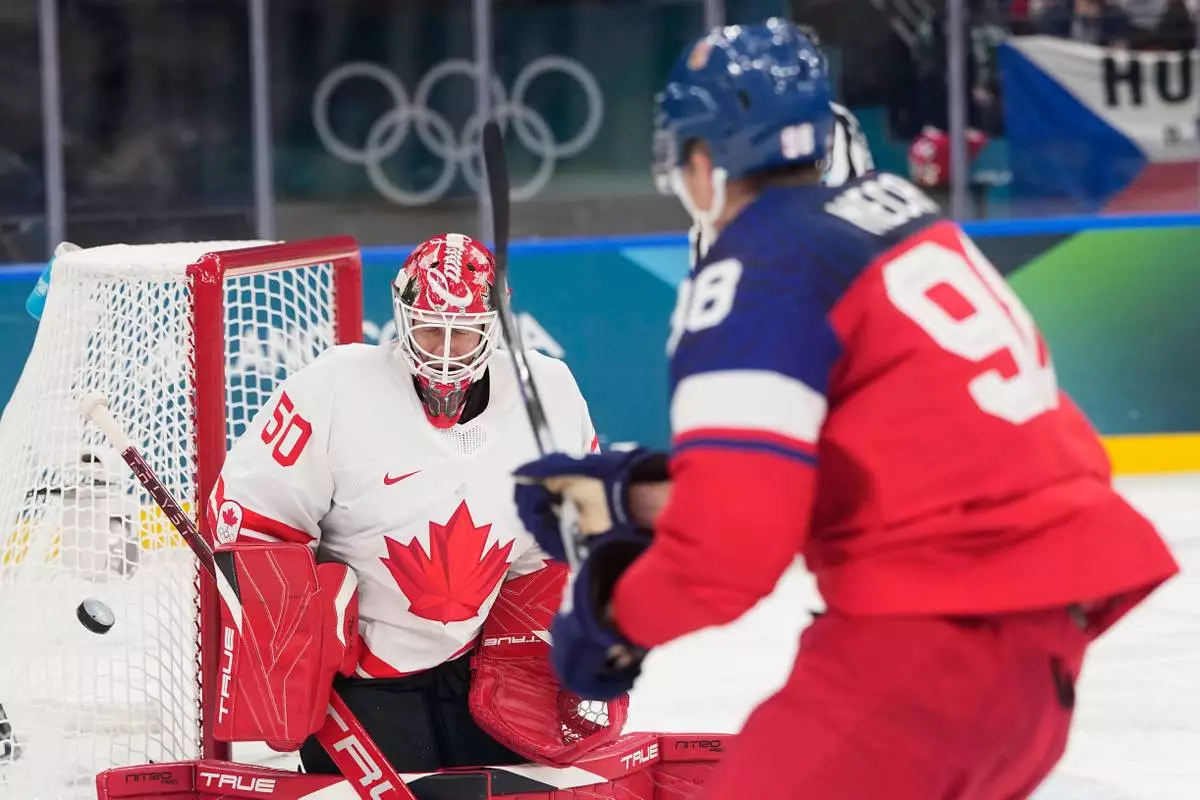 Czechia's Martin Necas, right, takes a shot at Canada's goalkeeper Jordan Binnington during a preliminary round match of men's ice hockey between Czech Republic and Canada at the 2026 Winter Olympics, in Milan, Italy, Thursday, Feb. 12, 2026. (AP Photo/Petr David Josek)