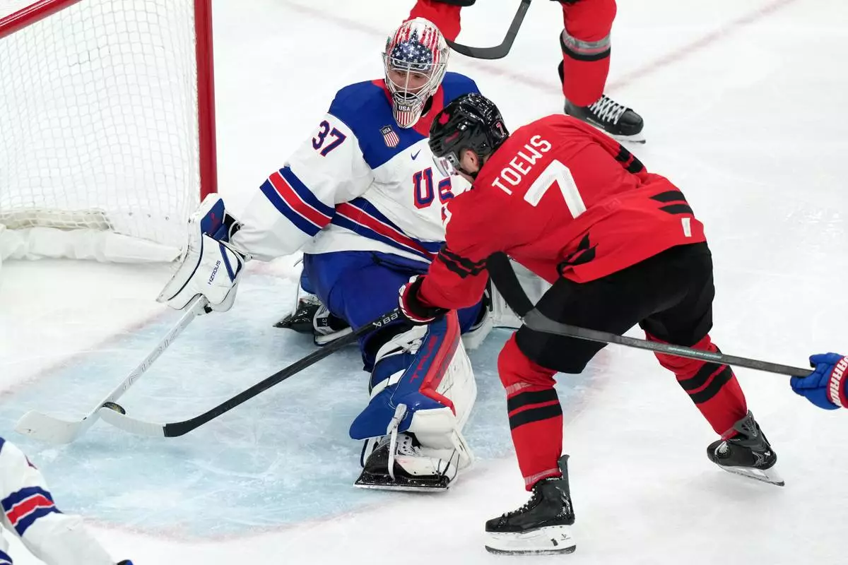 United States goalkeeper Connor Hellebuyck (37) uses his stick to block a shot by Canada's Devon Toews (7) during the third period of the men's ice hockey gold medal game at the 2026 Winter Olympics in Milan, Italy, Sunday, Feb. 22, 2026. (AP Photo/Carolyn Kaster)