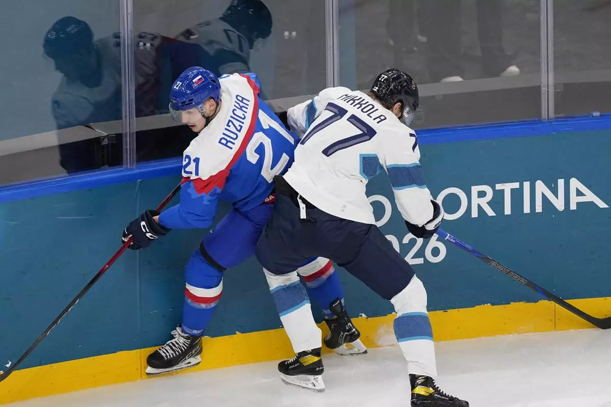 Slovakia's Adam Ruzicka (21), left, challenges Finland's Niko Mikkola (77) during a preliminary round match of men's ice hockey between Slovakia and Finland at the 2026 Winter Olympics, in Milan, Italy, Wednesday, Feb. 11, 2026. (AP Photo/Petr David Josek)