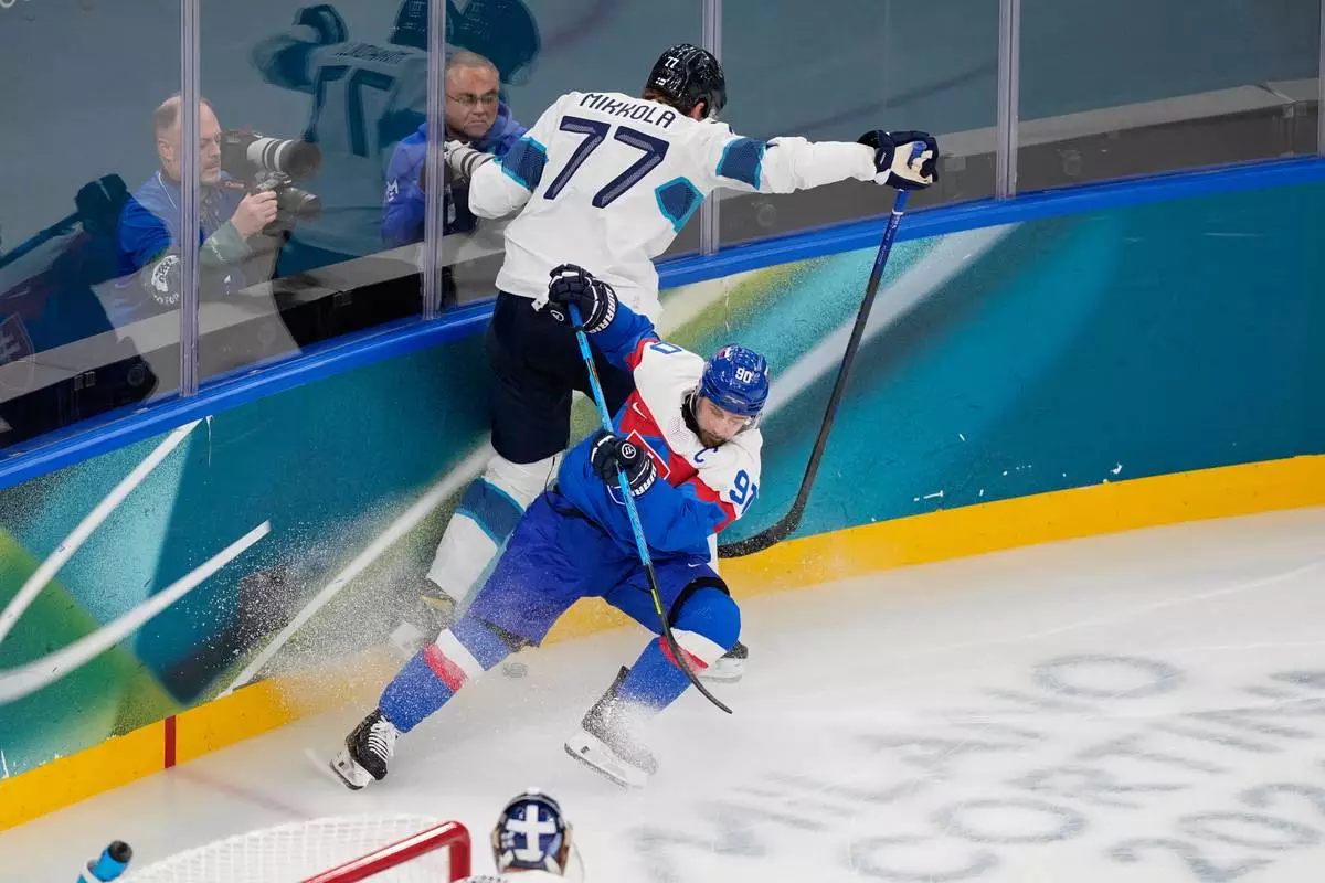Finland's Niko Mikkola (77)challenges Slovakia's Tomas Tatar (90) during a preliminary round match of men's ice hockey between Slovakia and Finland at the 2026 Winter Olympics, in Milan, Italy, Wednesday, Feb. 11, 2026. (AP Photo/Petr David Josek)