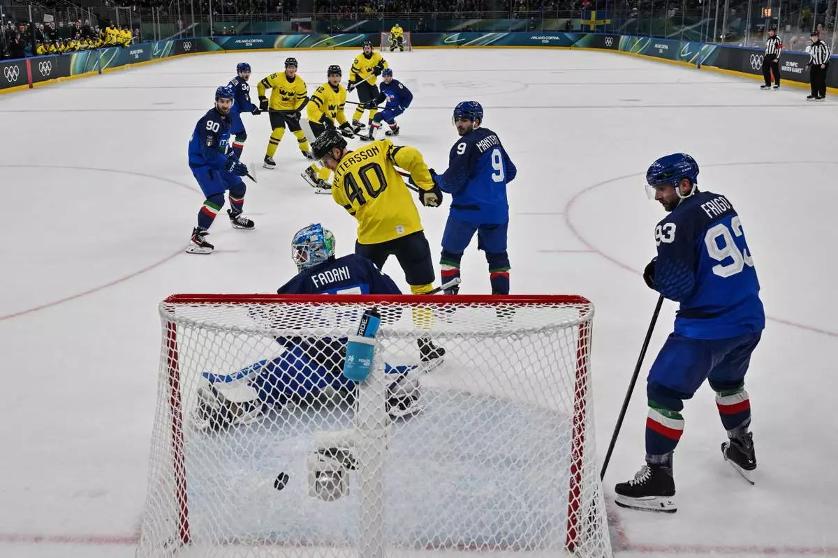 Sweden's Mika Zibanejad (rear C) shoots and scores his team fourth goal during the men's preliminary round Group B Ice Hockey match between Sweden and Italy at the 2026 Winter Olympics, in Milan, Italy, Wednesday, Feb. 11, 2026. (Alexander Nemenov/Pool Photo via AP)