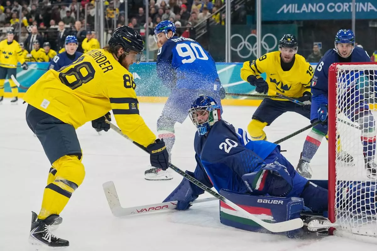 Italy's goalkeeper Damian Clara (20) makes a save against Sweden's William Nylander (88) during a preliminary round match of men's ice hockey between Italy and Sweden at the 2026 Winter Olympics, in Milan, Italy, Wednesday, Feb. 11, 2026. (AP Photo/Hassan Ammar)