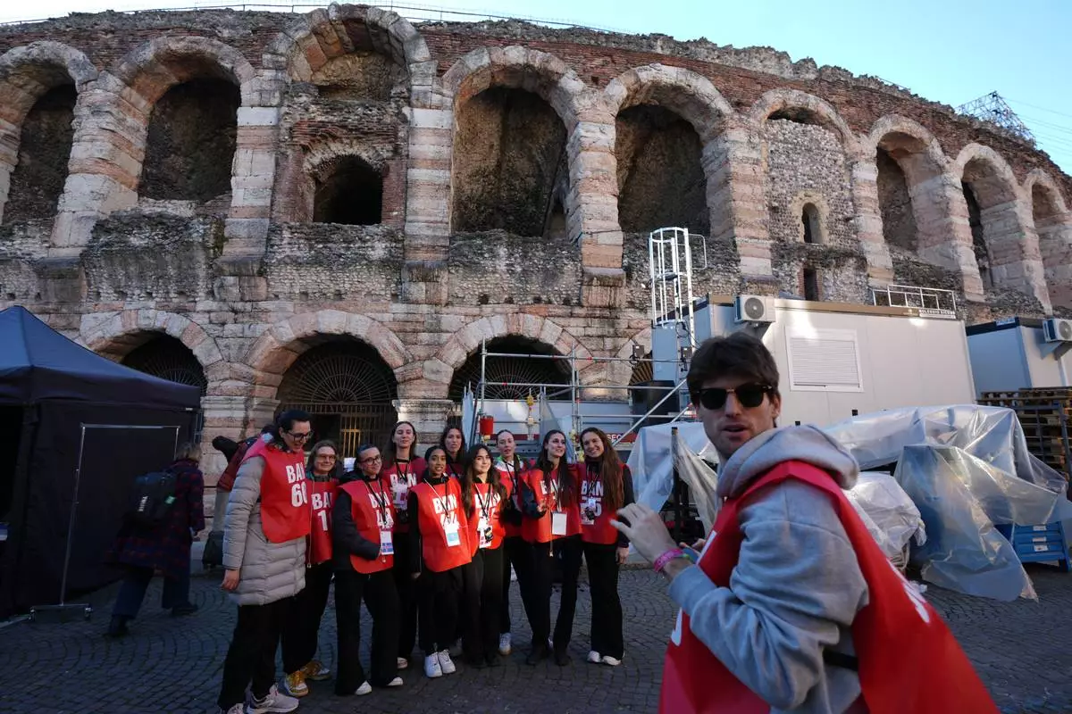 Volunteers stand close to the Arena ahead of the closing ceremony at the 2026 Winter Olympics, in Verona, Italy, Tuesday, Feb. 17, 2026. (AP Photo/Antonio Calanni)