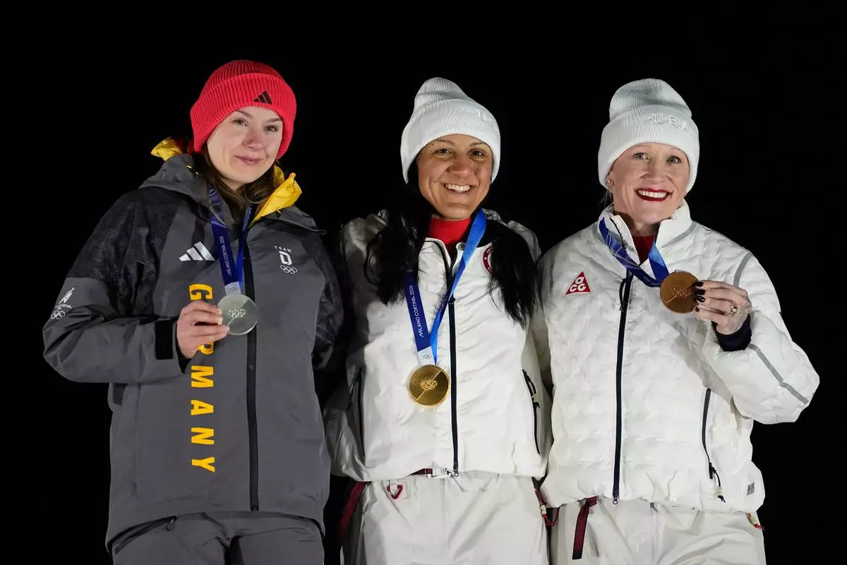 From left, Germany's silver medalist Laura Nolte, United States' gold medalist Elana Meyers Taylor and United States' bronze medalist Kaillie Armbruster Humphries pose for photos on the podium of a women's monobob competition at the 2026 Winter Olympics, in Cortina d'Ampezzo, Italy, Monday, Feb. 16, 2026. (AP Photo/Alessandra Tarantino)