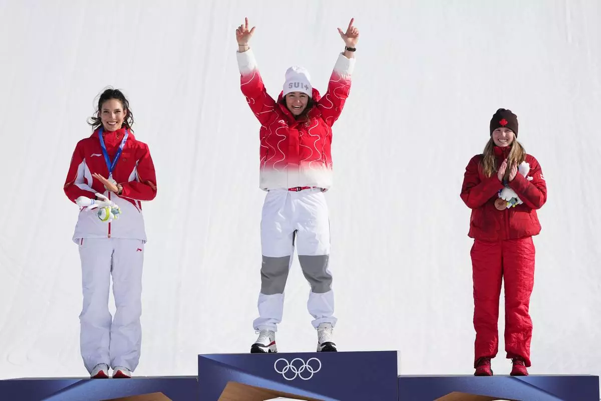 Gold medalist Switzerland's Mathilde Gremaud, center, celebrates alongside silver medalist China's Eileen Gu, left, and bronze medalist Canada's Megan Oldham after the women's freestyle skiing slopestyle finals at the 2026 Winter Olympics, in Livigno, Italy, Monday, Feb. 9, 2026. (AP Photo/Gregory Bull)
