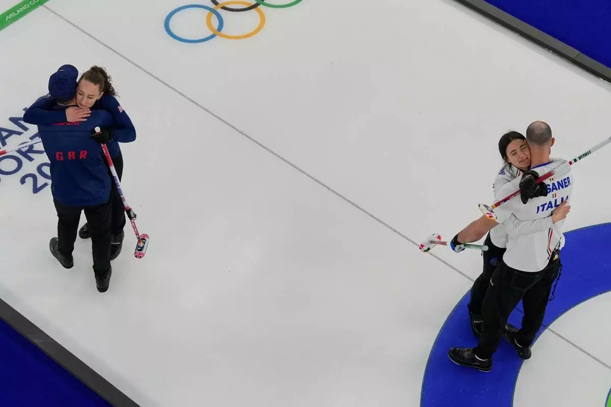 Italy's Amos Mosaner and Stefania Constantini, right, celebrate after winning the bronze medal mixed doubles curling match Britain's Bruce Mouat and Jennifer Dodds at the 2026 Winter Olympics, in Cortina d'Ampezzo, Italy, Tuesday, Feb. 10, 2026. (AP Photo/Bernat Armangue)