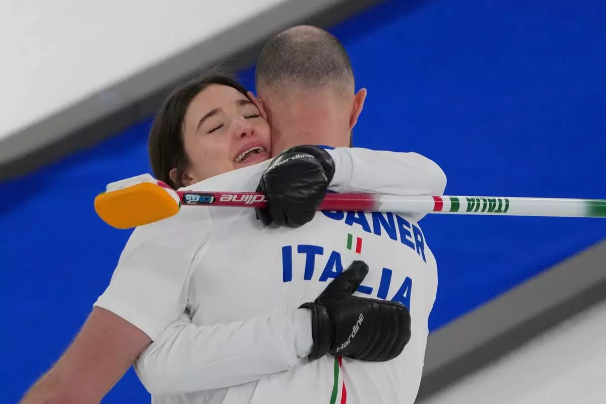 Italy's Amos Mosaner and Stefania Constantini celebrate after winning the bronze medal mixed doubles curling match against Britain, at the 2026 Winter Olympics, in Cortina D'Ampezzo, Italy, Tuesday, Feb. 10, 2026. (AP Photo/Misper Apawu)