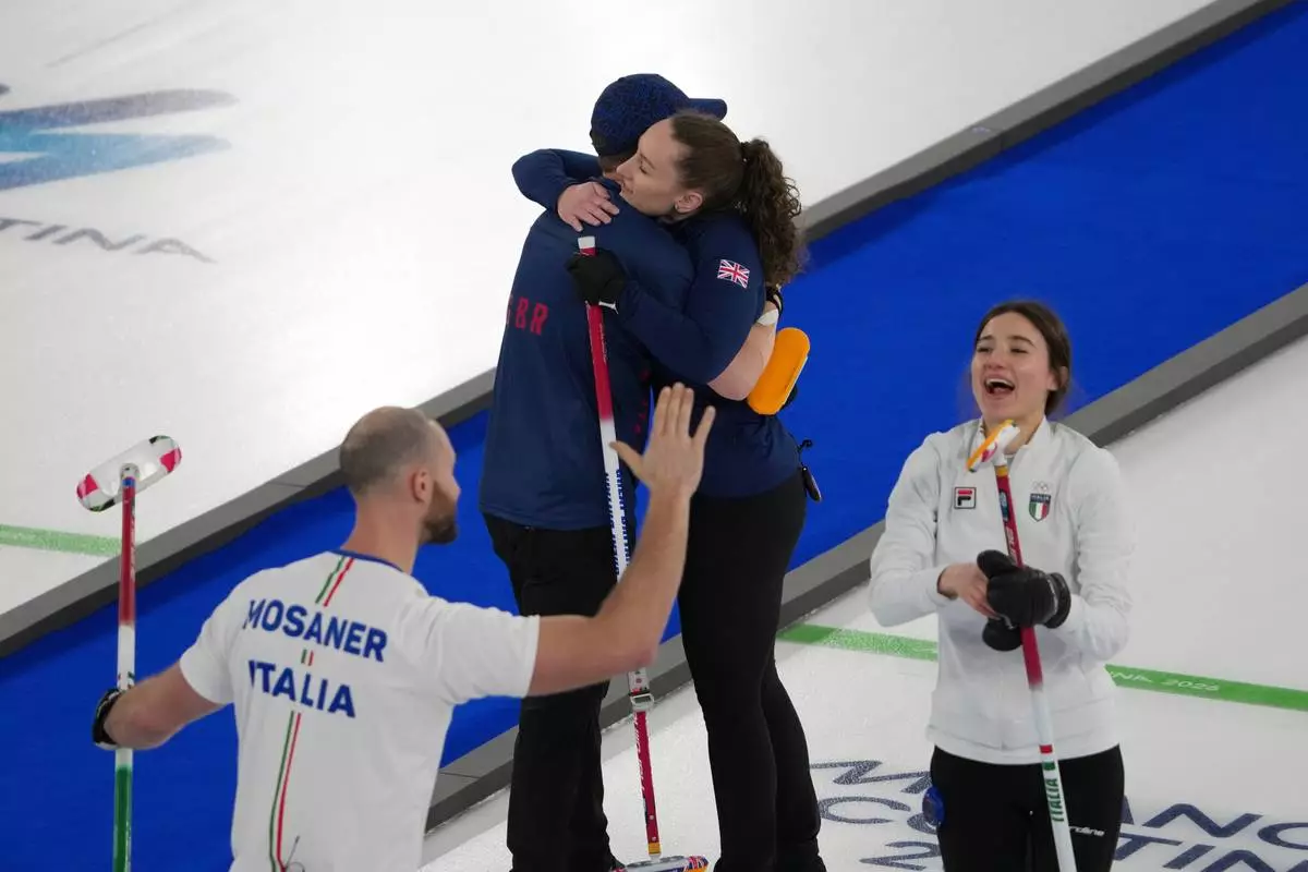 Italy's Amos Mosaner and Stefania Constantini celebrate as Britain's Bruce Mouat and Jennifer Dodds hug at the end of the bronze medal mixed doubles curling match, at the 2026 Winter Olympics, in Cortina D'Ampezzo, Italy, Tuesday, Feb. 10, 2026. (AP Photo/Misper Apawu)