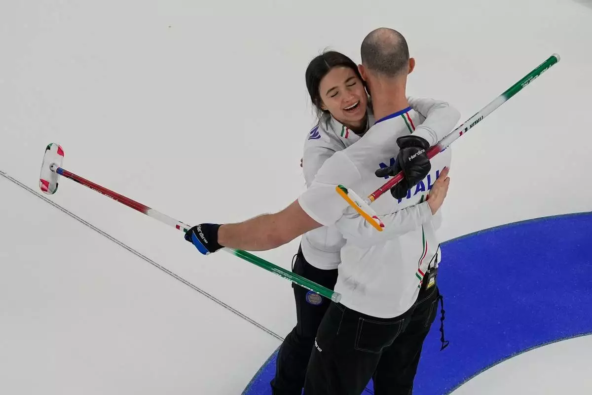 Italy's Amos Mosaner and Stefania Constantini celebrate after winning the bronze medal mixed doubles curling match, at the 2026 Winter Olympics, in Cortina D'Ampezzo, Italy, Tuesday, Feb. 10, 2026. (AP Photo/Bernat Armangue)