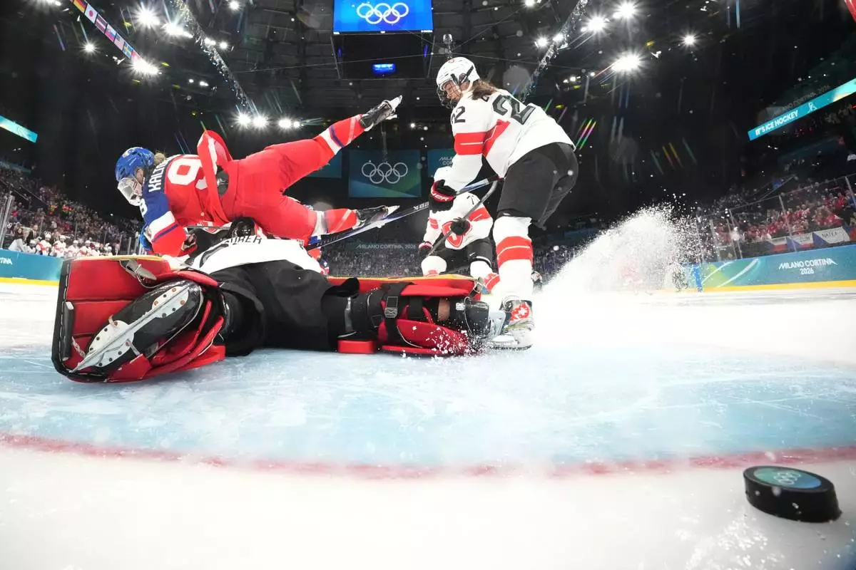 Czechia's Kristyna Kaltounkova, left, falls over Switzerland's Saskia Maurer while scoring her sides first goal during a preliminary round match of women's ice hockey between Switzerland and Czechia at the 2026 Winter Olympics, in Milan, Italy, Friday, Feb. 6, 2026. (David W Cherny/Pool Photo via AP)